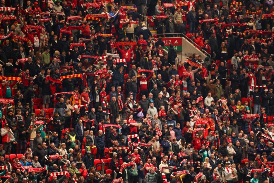 Fans at Anfield stadium holding up red and white scarves.