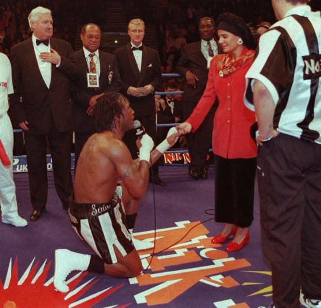a man in a boxing ring kneeling down with a woman standing behind him