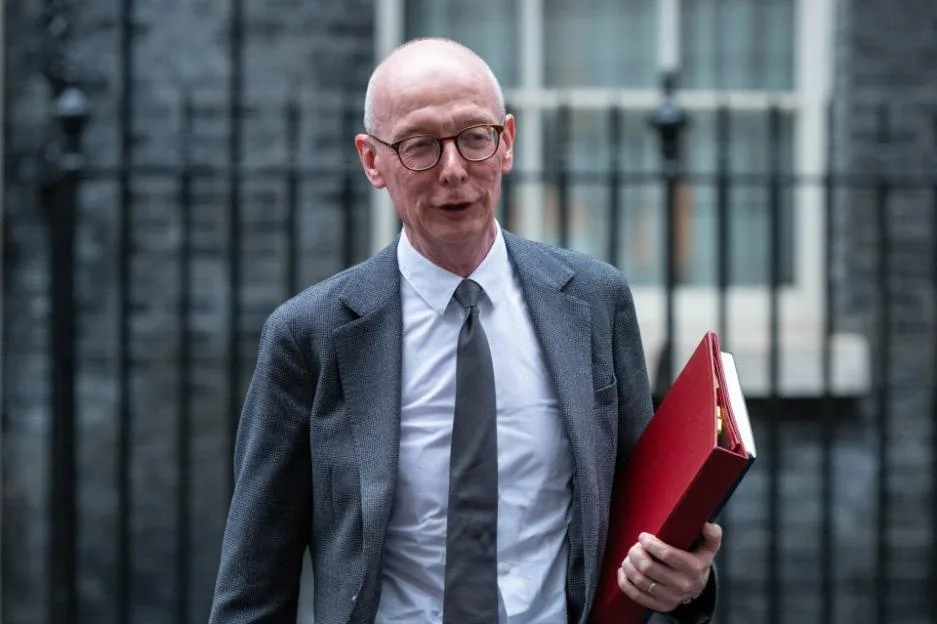 Cabinet minister carrying a red ministerial box outside Downing Street.