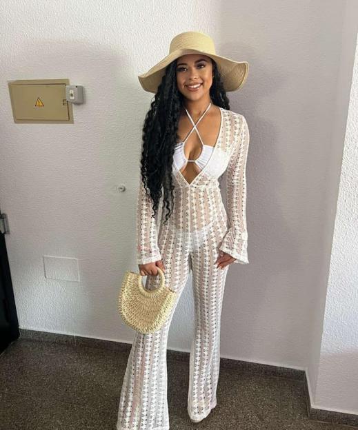 Eve Smith, wearing a straw hat, white bikini, and a white lace jumpsuit.
