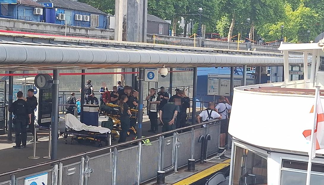 Police officers and medical personnel with a stretcher at a dock.