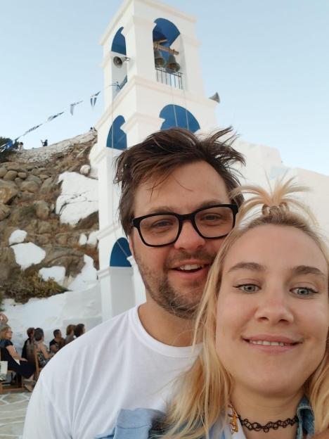 Matthew Pringle and Liv Nevro pose together with a church bell tower in the background.