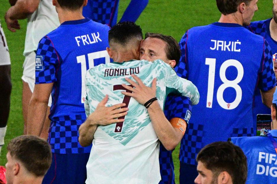 A soccer player wearing a white jersey with "RONALDO" and the number "7" on the back is hugging another player in a blue jersey.