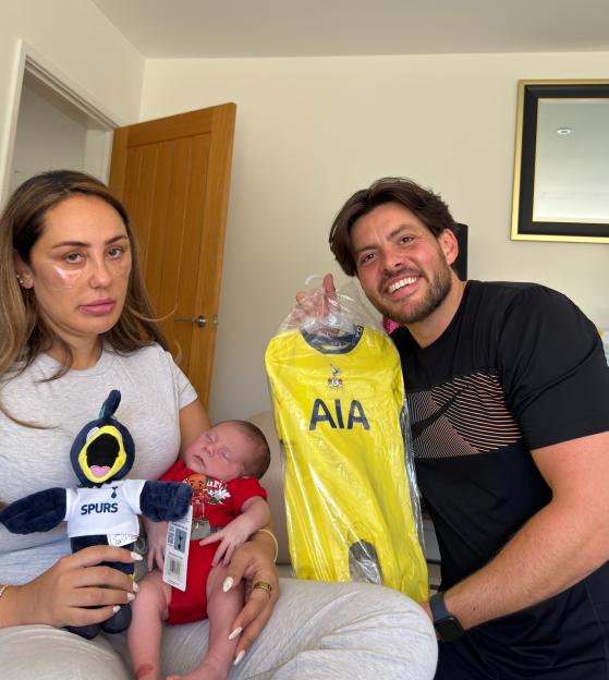 Sophie Kasaei and Jordan Brooks pose with their baby, Brody, and a Tottenham Hotspur football kit.