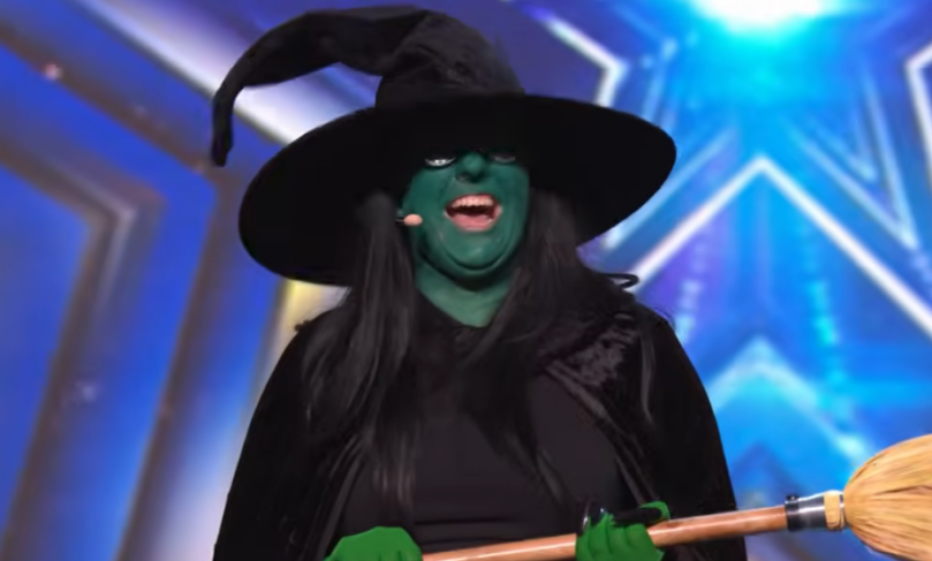 A performer dressed as the Wicked Witch of the West, with green face paint and a black hat, holding a broomstick.
