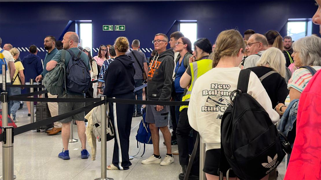 People in a long queue at Newcastle Airport terminal for security clearance.