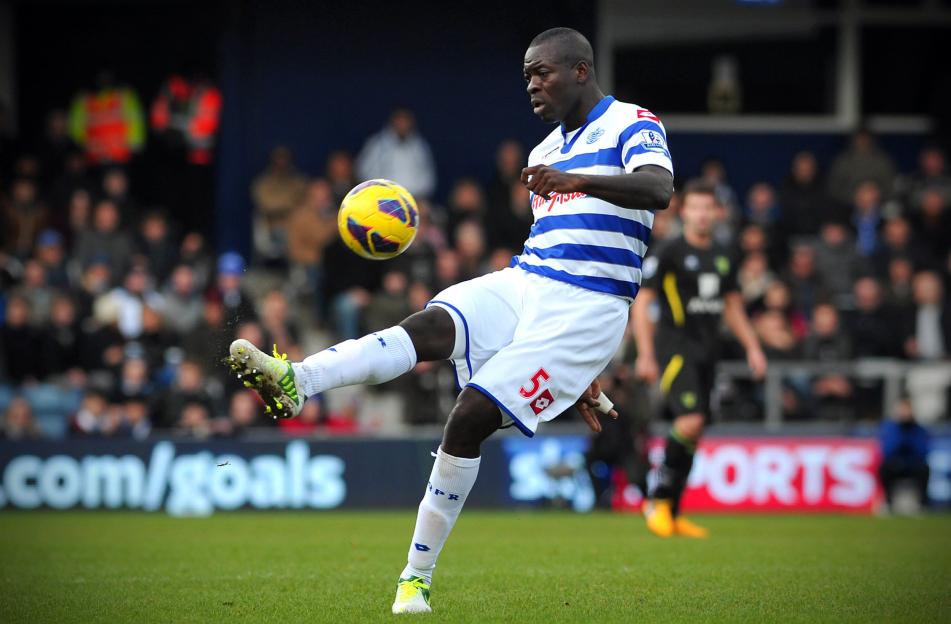 A soccer player in a white and blue striped jersey kicking a yellow soccer ball.