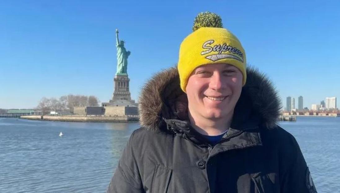 Ryan Phillips smiling with the Statue of Liberty in the background.