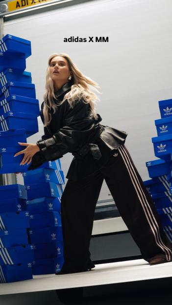 Molly Mae wearing an Adidas outfit and surrounded by stacks of Adidas shoe boxes.