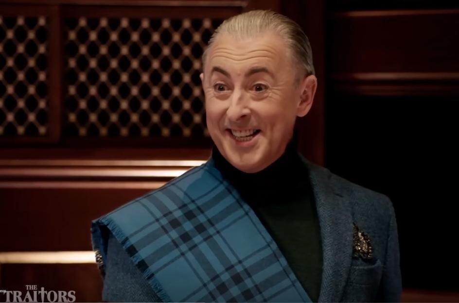 Alan Cumming, host of Traitors US, is smiling.