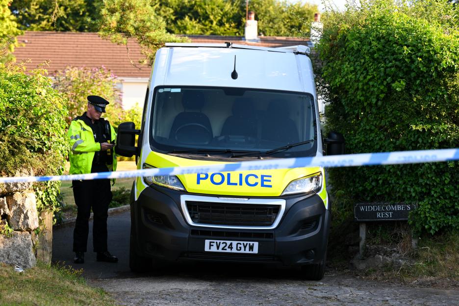 A police officer stands next to a police van outside the home of Ann Widdecombe in Dartmoor, United Kingdom.