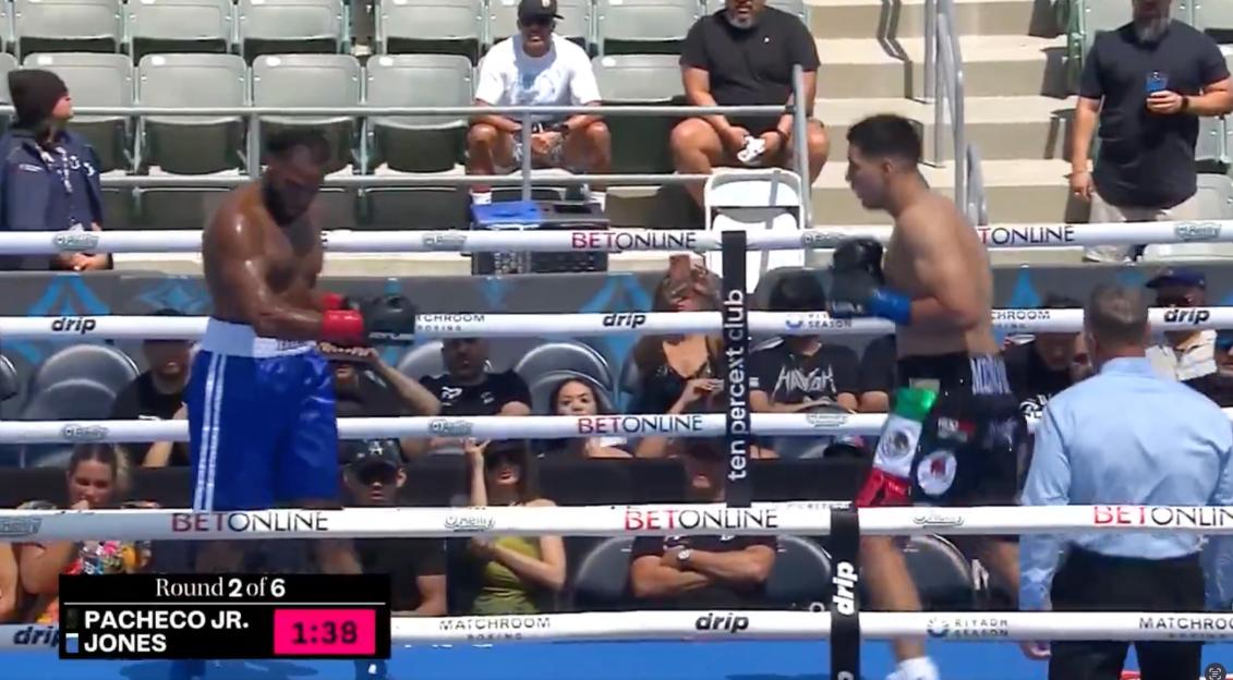 Two boxers in a ring with a referee, a digital scoreboard showing "Round 2 of 6 PACHECO JR. JONES 1:38" and "BETONLINE" branding visible on the ropes.
