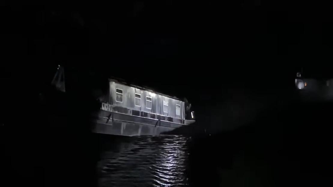 Canal boat sinking into a sinkhole at night.
