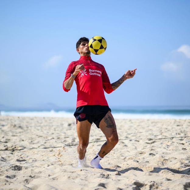 Piero Hincapie juggling a yellow and black soccer ball on a sandy beach.