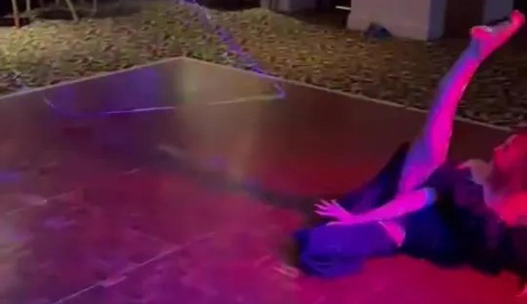 A woman in a black dress on a dance floor, her leg raised high in the air, with a caption about flashing her dad at her brother's wedding.