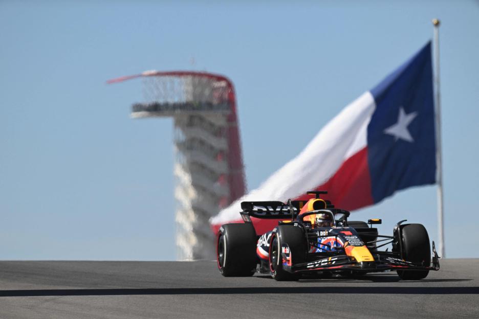 Max Verstappen in a Red Bull Racing car on the track with a Texas flag and observation tower in the background.