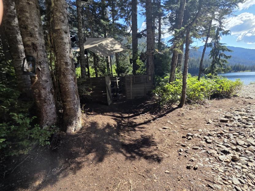 Wild Frontier set near a lake with wooden structures and a lantern hanging from a tree.