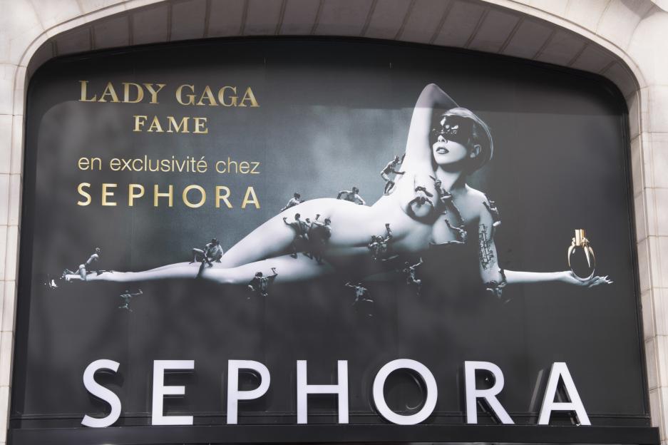 Advertisement for Lady Gaga's Fame Eau de Parfum at Sephora, showing Lady Gaga with tiny men climbing over her body.