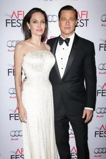 Angelina Jolie and Brad Pitt pose together on a red carpet in formal attire.