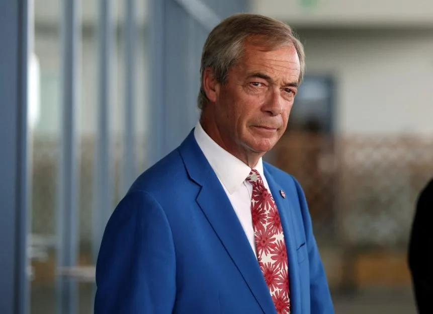 Reform UK party leader Nigel Farage looks on as he speaks to a television crew.