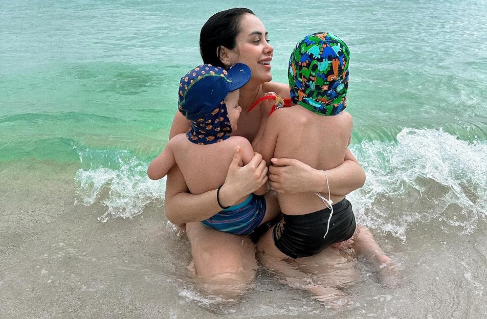 Marnie Simpson sitting in the ocean with her two young sons.