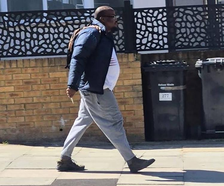 Man walking on a sidewalk, carrying a knife.