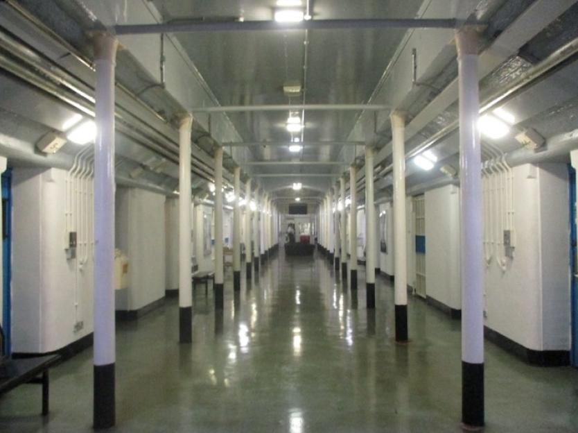 The long, brightly lit corridor inside HMP Preston prison, lined with white pillars and cell doors.