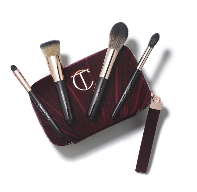 Charlotte Tilbury makeup brush set with a burgundy velvet pouch.