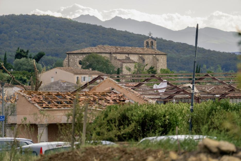 Damaged buildings and a church with a bell tower are visible among mountains in France.