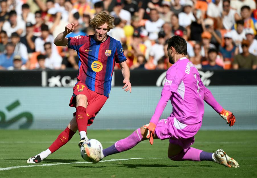 Anthony Gordon of Barcelona runs with the ball under pressure from Ivan Balliu of Rayo Vallecano during a soccer match.