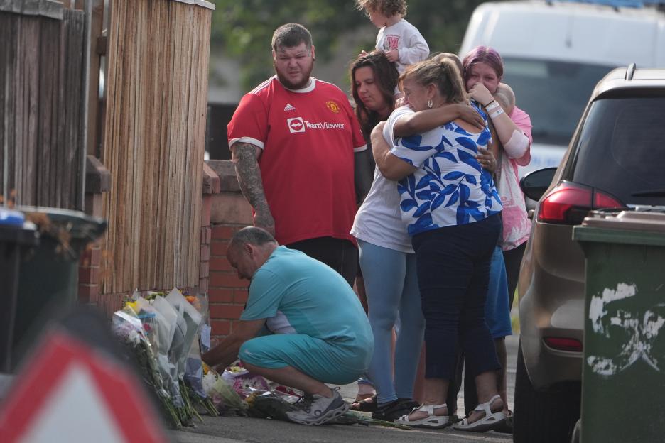 People laying flowers at the scene of a fatal house fire.
