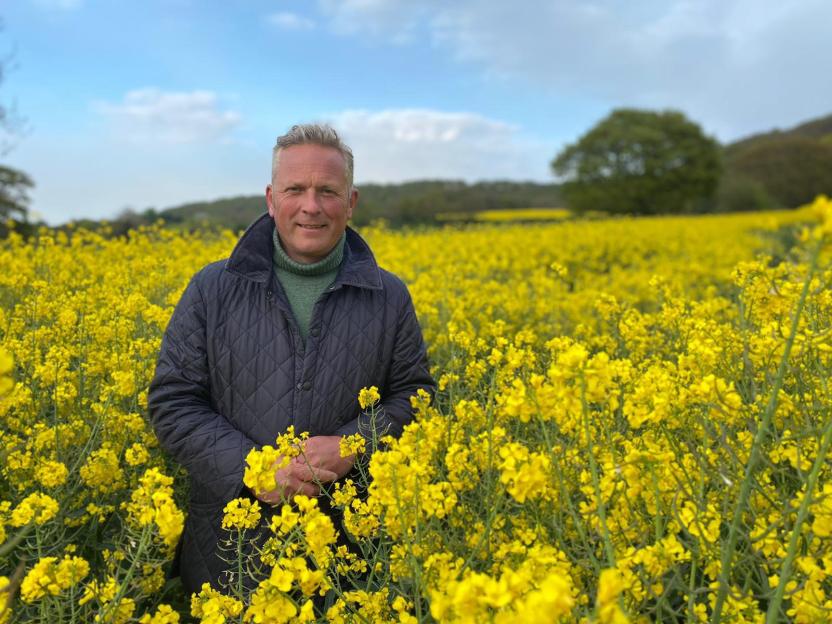 Jules Hudson, a presenter, standing in a field of yellow flowers.