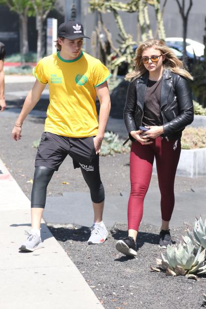 Chloe Grace Moretz and Brooklyn Beckham walk together on a sunny day.