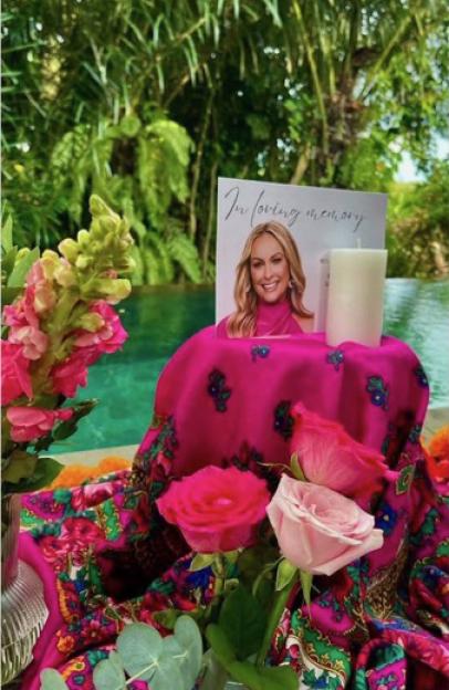 Memorial display for Mel Schilling with a photo, candle, flowers, and a pink scarf.