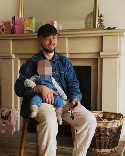 William Rush holding his baby son Frankie on his lap, smiling at someone off-camera.
