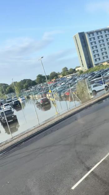 Flooded airport car park with vehicles submerged in water.
