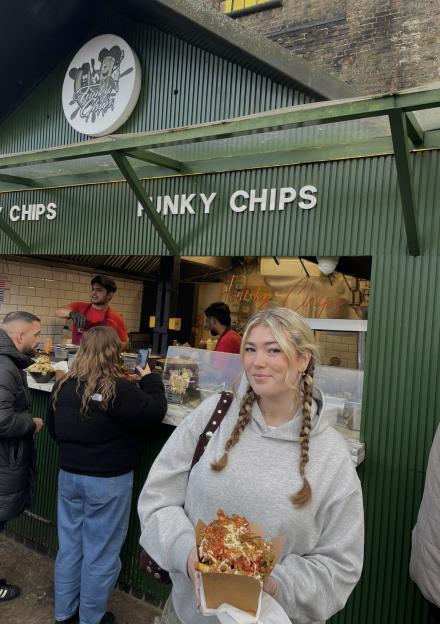 A woman holding a box of Funky Chips in front of the Funky Chips food stall.