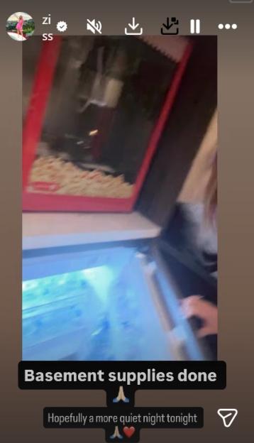 A person with an open mini-fridge and a popcorn maker filled with popcorn.