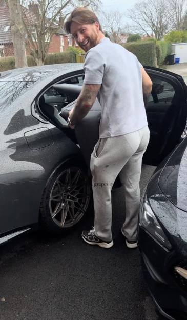 Man loading items into the back seat of a car.