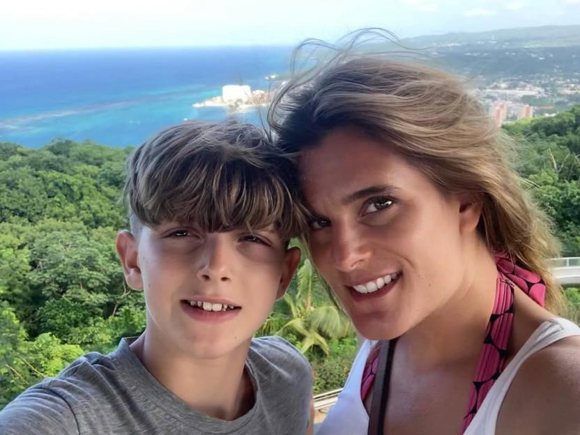 Ellen Roome and her son Jools Sweeney smiling for a photo, with a mountainous, coastal landscape behind them.