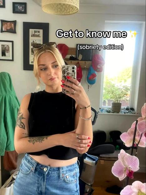 A woman taking a mirror selfie with text overlay "Get to know me (sobriety edition)".