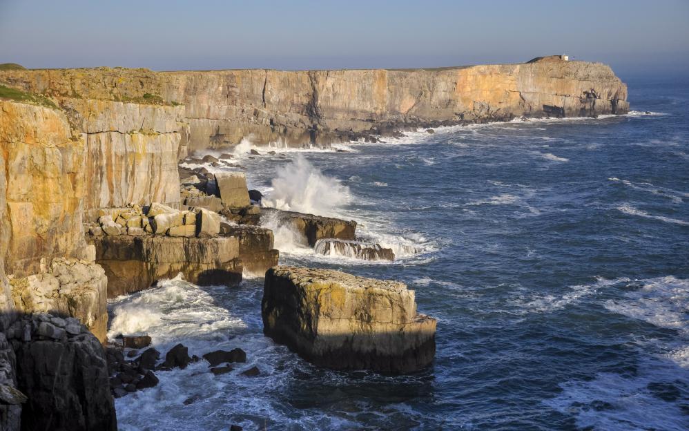 Waves crash against limestone cliffs at St. Govan's Head in Pembrokeshire, Wales.