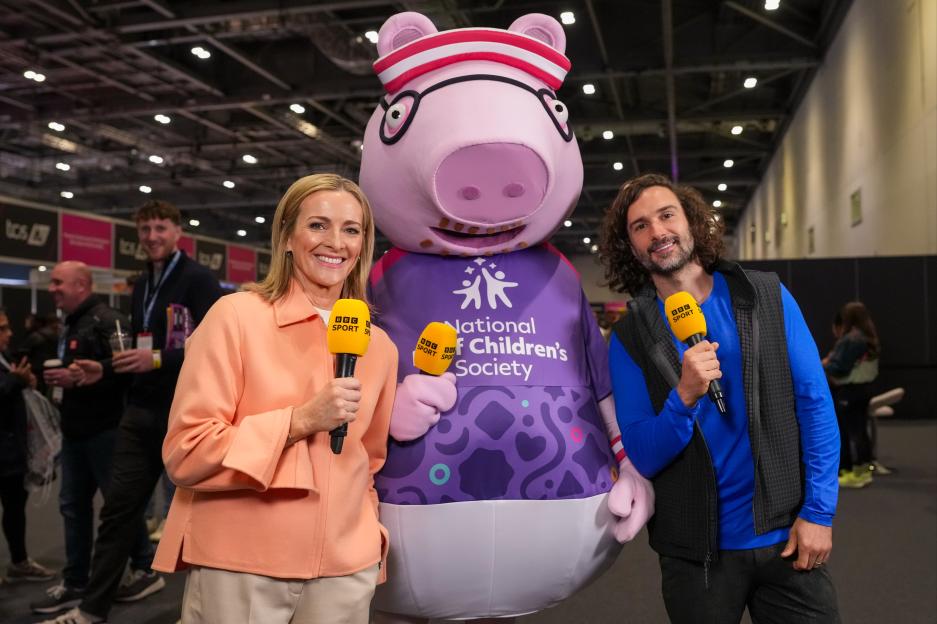 Gabby Logan and Joe Wicks hold BBC Sport microphones while posing with Daddy Pig, who is wearing a shirt for the National Children's Society.