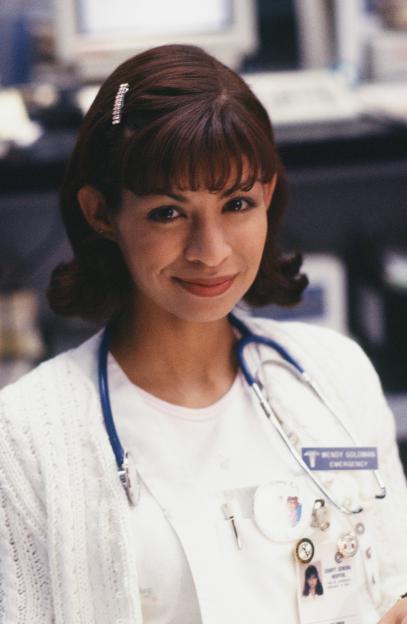 Vanessa Marquez as Nurse Wendy Goldman in a white cardigan and blue stethoscope.