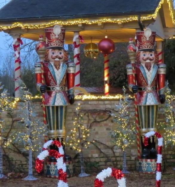 Two 10ft tall nutcracker figures in red and gold outfits guarding a festive home.
