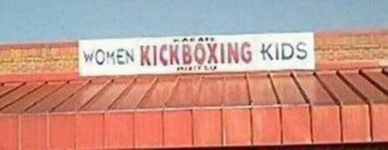 Sign reading "Women Kickboxing Kids" above a building.