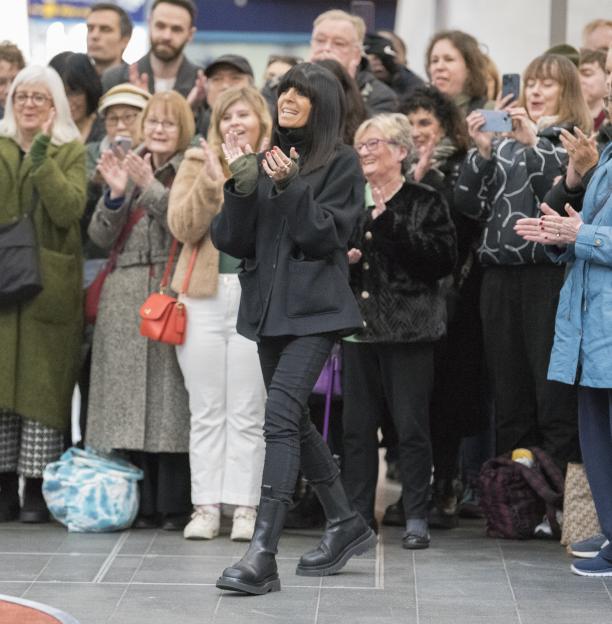 Claudia Winkleman walking past a clapping crowd.
