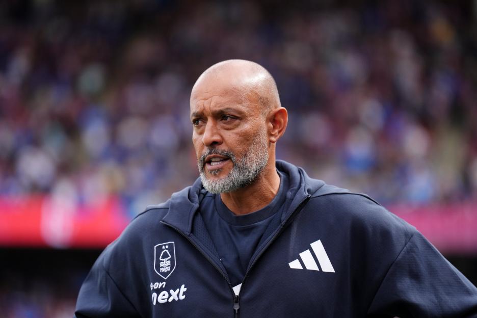 Nuno Espirito Santo, a bald man with a gray beard, wearing a dark blue athletic top with a team logo and Adidas stripes, looks intently to his left.
