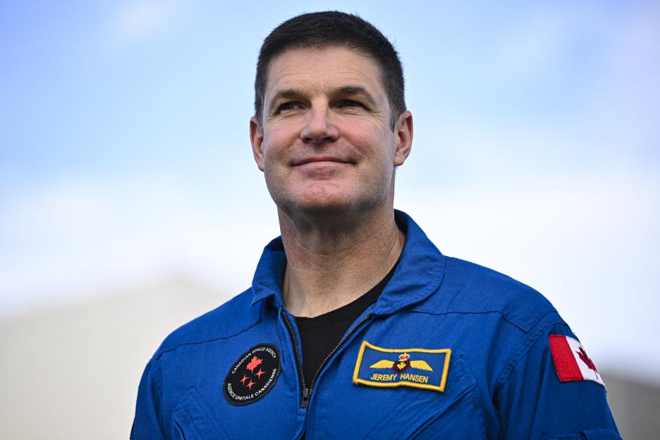 Canadian Space Agency astronaut Jeremy Hansen in a blue flight suit looks up and to the right.