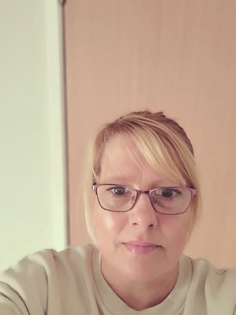 Natalee Gibbings, a woman with blonde hair and glasses, looking directly at the camera.